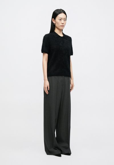 Sort polo i mohairblanding med korte ærmer; kombineret med mørkegrå bukser med brede ben og striber. Simpelt, tekstureret design.