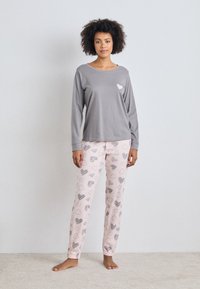 Grå långärmad tröja med hjärtmotiv; rosa pyjamasbyxor med olika hjärt-mönster; mjukt tyg; lös passform; avslappnad loungeklädsel.