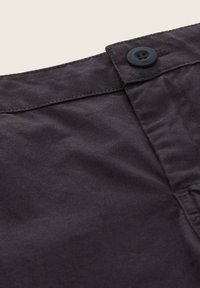 Donkergrijze katoenen broek met een vlakke voorkant, knoopsluiting en subtiele structuur. Inclusief zijzakken en netjes gestikte naden.