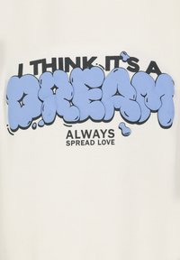 Weißes T-Shirt mit einem auffälligen blauen Bubble-Letter-Design, das "ICH DENKE, ES IST EIN TRAUM" über "VERBREITE IMMER LIEBE" in schwarzem Text anzeigt.