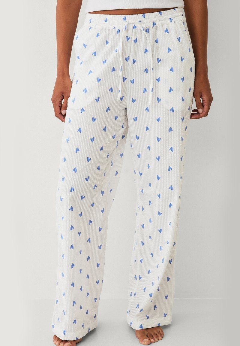 Witte pyjamabroek van een structuurstof, met een blauw hartjesprint, elastische tailleband met trekkoord en zijzakken.