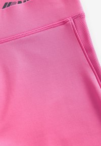 Shorts de sport roses en tissu lisse et extensible avec un panneau en maille. Comprend une taille plate et des détails de couture subtils.