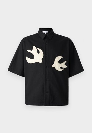 Chemise noire à manches courtes avec deux silhouettes de oiseaux crème brodées sur le devant. Col classique, devant boutonné, coupe décontractée.