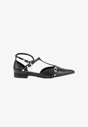 Zapato plano de cuero negro con punta afilada, doble correa en el tobillo y acentos en tono dorado. Presenta un tacón cuadrado bajo y una textura suave.