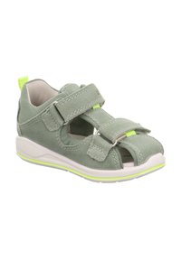 Sandal in suede verde con cinturini in Velcro regolabili, lati aperti e suola leggera bianca con una linea di accento gialla.