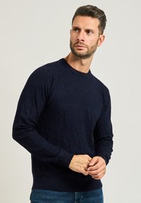 Maglione lavorato a maglia blu navy con un motivo geometrico testurizzato, scollo a giro e polsini e orlo a coste.
