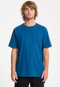Blaues Baumwoll-T-Shirt mit Rundhalsausschnitt und kurzen Ärmeln. Verfügt über ein kleines schwarzes Logo auf der linken Brust. Glatte Textur, lässiger Schnitt.