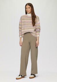 Gebreide trui met pastelstrepen, ronde halslijn en verlaagde schouders. Hoog getaileerde beige broek, met een brede pijp, gecombineerd met sneakers.