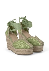 Zoccoli espadrille intrecciati verdi con tomaia testurizzata e lacci in raso alla caviglia. Presentano una suola intermedia in juta intrecciata e un design della punta arrotondato.