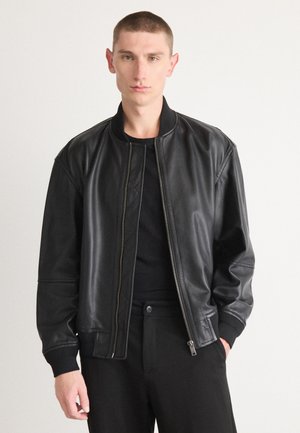 Black leather bomber jacket with a zip closure, ribbed cuffs, and a casual fit. Soft texture and sleek design with a minimalistic style.