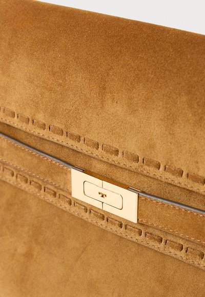 Borsa in camoscio color cuoio con una texture liscia, caratterizzata da una chiusura in metallo dorato e dettagli cuciti lungo il bordo per un tocco di design in più.