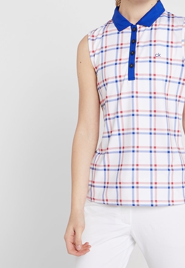 Ärmlös polo tröja i vitt med en blå krage. Har ett rutigt mönster i röd och blå. Tillverkad av ett lent, lätt tyg.