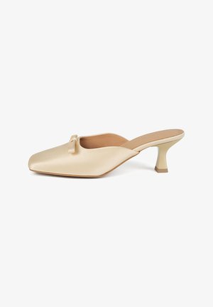 Beige satijnen open-back hakken mules met een vierkante neus, een lichte hak en een klein strikje als accent op de wreef. Glad textuur, minimalistisch ontwerp.