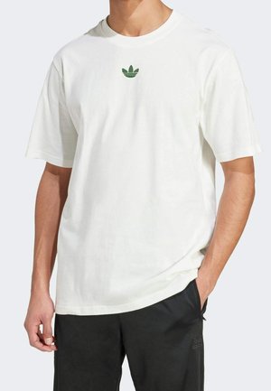 Biała bawełniana koszulka z krótkim rękawem i okrągłym dekoltem, z małym zielonym logo adidas Trefoil na piersi.