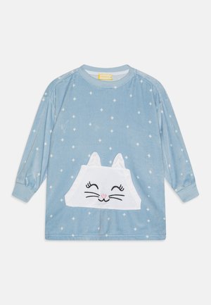 Chemise à manches longues en velours bleu avec une poche en forme de chat blanc, dotée d'un visage brodé et d'un nez rose, accentuée par des motifs d'étoiles blanches.