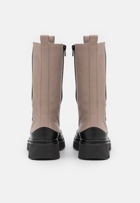 Béžové kožené ankle boots s čiernou špičkou a masívnou podrážkou, s recesívnym zipsom a pútkom pre jednoduché obúvanie.