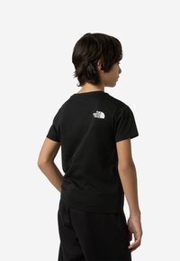 Μαύρο βαμβακερό μπλουζάκι με στρογγυλή λαιμόκοψη και κοντά μανίκια, με λευκό λογότυπο στην επάνω πλάτη. Μαλακή υφή και κανονική εφαρμογή.