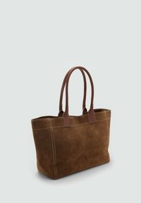Sac fourre-tout en suède brun avec double anses en cuir et surpiqûres visibles sur un fond gris clair.