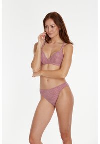 Grudnjak i bikini set u crvenoj boji s geometrijskim uzorkom. Grudnjak ima izrez u obliku slova V i široke naramenice; bikini ima klasičan kroj.