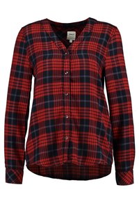 Chemise à carreaux rouges et bleu marine à manches longues, col en V, fermeture à boutons et ourlet arrondi. Confectionnée en tissu texturé, avec des motifs contrastants.