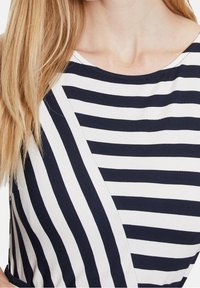 Navy and white striped top with a scoop neckline. Features horizontal and diagonal stripes, made from soft fabric, showing contrasting sections.