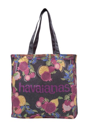 Bolsa tote con fondo oscuro, patrones coloridos de frutas y logo morado de "havaianas", con dos asas largas y oscuras.