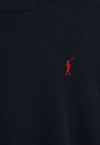 Suéter de punto azul marino con cuello acanalado y un pequeño logo bordado en rojo de una figura sosteniendo un palo de golf en el lado izquierdo del pecho.