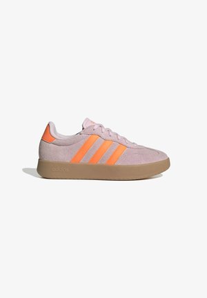 Lichtroze suède Adidas sneaker met oranje strepen en hieltab, bruine rubberen zool, veterontwerp, zijaanzicht op witte achtergrond.