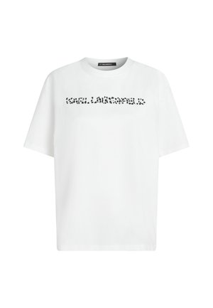 Balts īsām piedurkņu T-krekls ar apaļu kakla izgriezumu un melnā raibā teksta logotipu pāri krūtīm, kas saka "KARL LAGERFELD."
