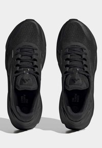Black athletic shoes with a textured upper, featuring flat laces, a padded collar, and a rubber sole; "END PLASTIC WASTE" printed inside.