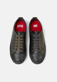 Schwarze und olivgrüne Leder-Sneaker mit kontrastierenden Schnürsenkeln, ausgestattet mit Gummisohlen und roten Innensohlen, die mit "CAMPE" und "TWINS" gekennzeichnet sind.