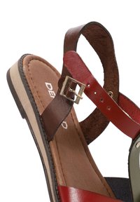 Leather sandal in red, brown, and green with adjustable straps, metallic buckle detail, and a low, multi-layered sole.