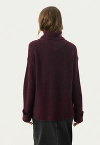 Langetermijnsweater met hoge hals in diep bordeauxrood, vervaardigd uit zachte breimateriaal met een relaxte pasvorm en opgerolde manchetten voor extra textuur.