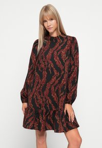 Black dress with long sleeves, ruffled hem, and red leaf pattern. Soft fabric and loose fit, featuring a high neckline and gathered shoulders.