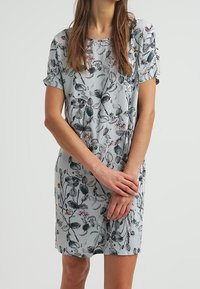 Ljusblå klänning med korta ärmar och ett blommönster i mörkgrön och rosa. Mjuk kvalitet med en avslappnad passform.