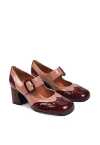 Bordowe lakierowane szpilki z beżowymi akcentami, okrągły czubek i dekoracyjne wycięcia. Zawierają zapięcie na klamrę oraz teksturowany blokowy obcas.