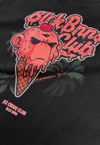 Zwarte T-shirt met een levendige afbeelding van een aap die van ijs gaat, met een hoorntje en palmbomen eromheen. Tekst leest "IJsclub."