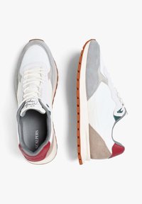 Zapatillas blancas y grises con acentos rojos en el talón, suelas de goma marrón y cordones blancos, mostradas desde vistas superior y lateral sobre un fondo blanco.