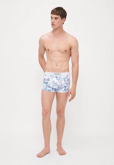 Boxer shorts pour hommes en blanc avec un motif floral bleu. Ceinture élastique avec l'étiquette "VERSACE". Design ajusté avec une texture lisse.