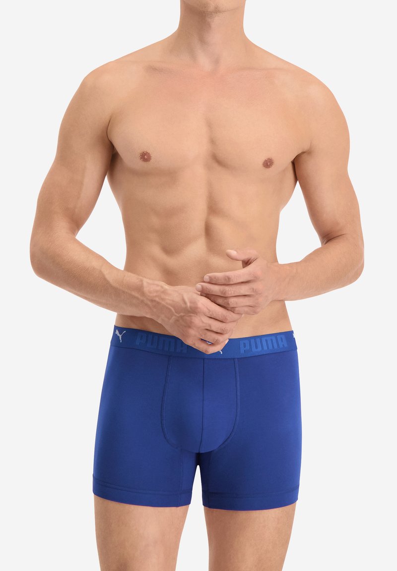 Blaue Baumwollboxershorts mit einem logoartigen Bund. Eng anliegendes Design mit einer glatten Textur und mittellangem Schnitt. Leicht konturiertes Vorderteil.