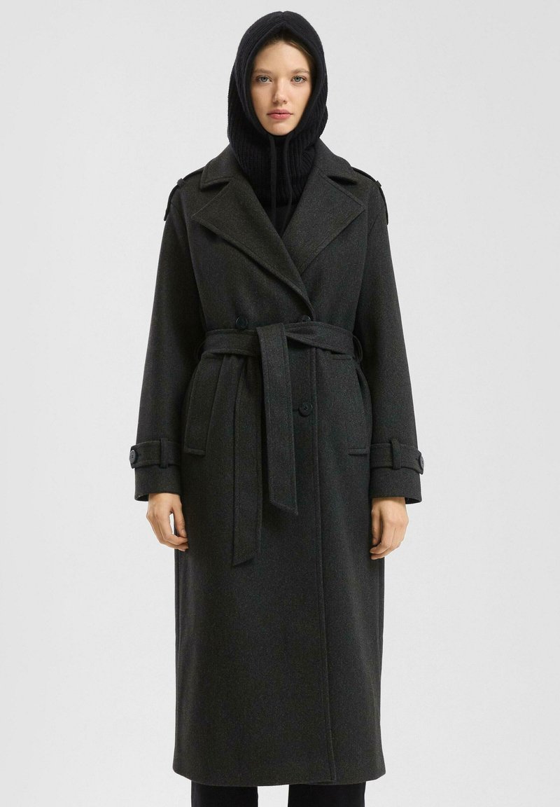 Lange zwarte wollen jas met een dubbelrijg ontwerp, brede revers, een riem in de taille en knoopmanchetten. Bevat een zwarte gebreide capuchon.