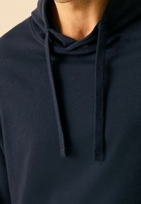 Granatowy hoodie z kieszenią z przodu, regulowanymi sznurkami oraz miękkim, fakturowanym materiałem, z kieszenią kangurką na przedzie.