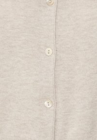 Beige gestrickte Strickjacke mit V-Ausschnitt, vier weißen Knöpfen an der Vorderseite und einem weichen, strukturierten Stoff.