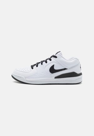 Scarpe sportive bianche con dettagli neri, dotate di una tomaia simile alla pelle, punta forata e suola imbottita per il supporto.