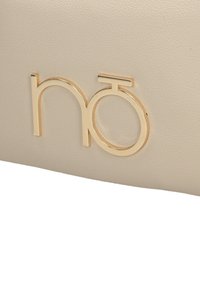 Pochette in finta pelle beige con il logo dorato "hō" in evidenza impresso sul fronte. Texture liscia con dettagli di grana sottili.