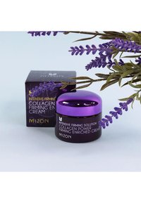 Dunkellila Glascremebehälter mit glänzendem lilanem Deckel, beschriftet mit "Intensive Firming Solution Collagen Power Firming Enriched Cream." Schachtel im Hintergrund.
