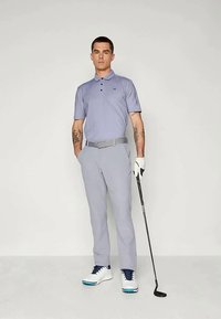 Γκρι γκολφ παντελόνι, ανοιχτό μωβ πόλο πουκάμισο, λευκά γκολφ παπούτσια με μπλε λεπτομέρειες. Ο χαρακτήρας κρατάει μια γκολφ ρακέτα, με αξιοσημείωτα τατουάζ ορατά.