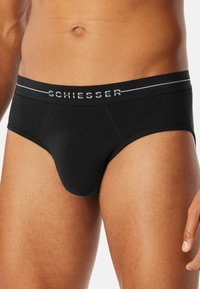 Svart bomullsbrief med logoband, grå detaljer, slät textur och en åtsittande design med en definierad framficka.