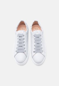 Ζευγάρι άσπρα δερμάτινα αθλητικά παπούτσια με φαρδιές γκρι ελαστικές κορδόνια και λογότυπο "AGL" στη γλώσσα, φαίνονται από πάνω σε λευκό φόντο.