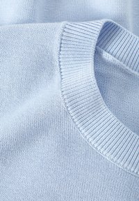 Svijetloplava pletena majica s rebrastim okovratnikom i finom teksturom, koja prikazuje glatku tkaninu s nešto rastezljivim kvalitetama.